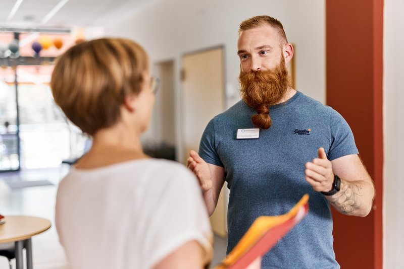 Zwei Mitarbeitende auf einem Stationsflur sprechen miteinander (Symbolbild)