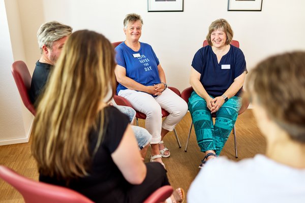 Eine Gruppe sitzt im Kreis und bespricht sich (Symbolbild)